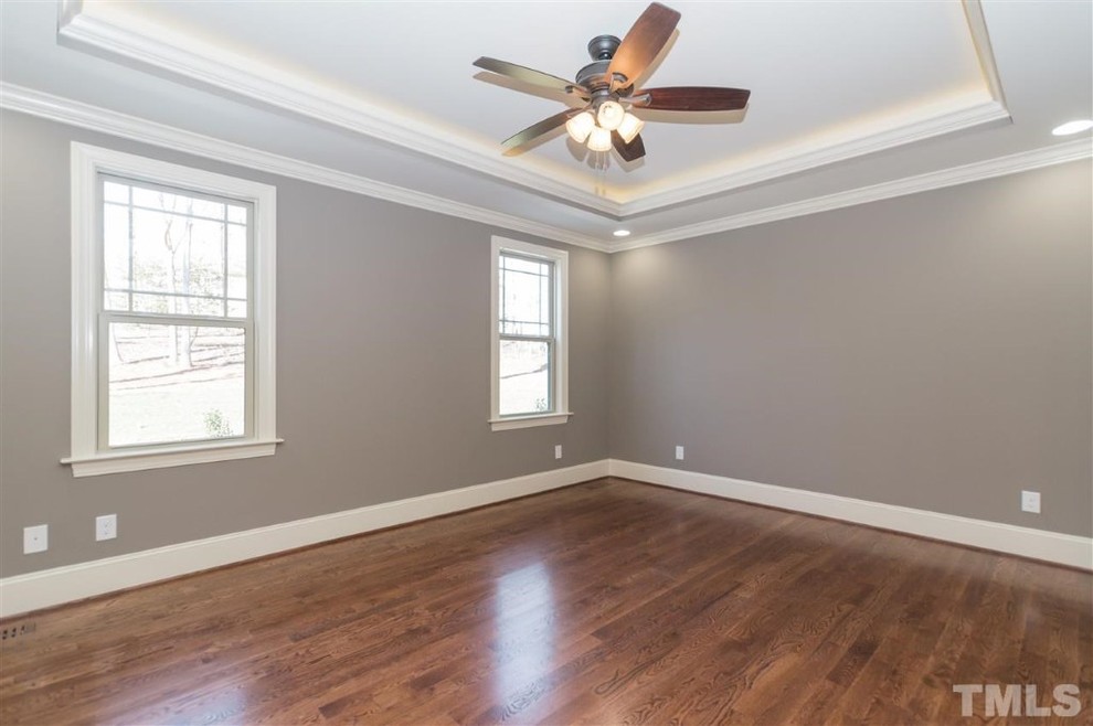 This is an example of a large arts and crafts master bedroom in Raleigh with grey walls, medium hardwood floors and no fireplace.