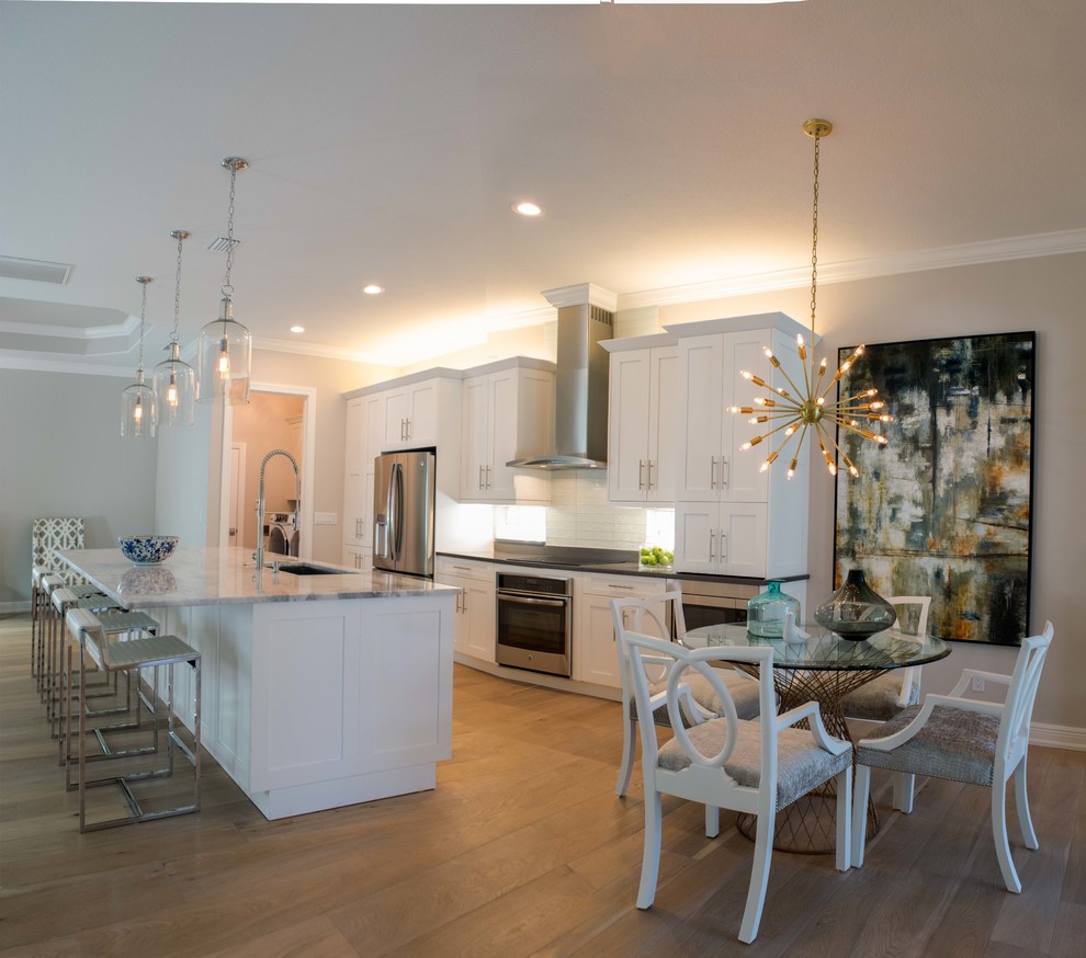 Mid-sized transitional single-wall light wood floor and beige floor open concept kitchen photo in Miami with shaker cabinets, white cabinets, marble countertops, white backsplash, stainless steel appliances, an island, an undermount sink and subway tile backsplash