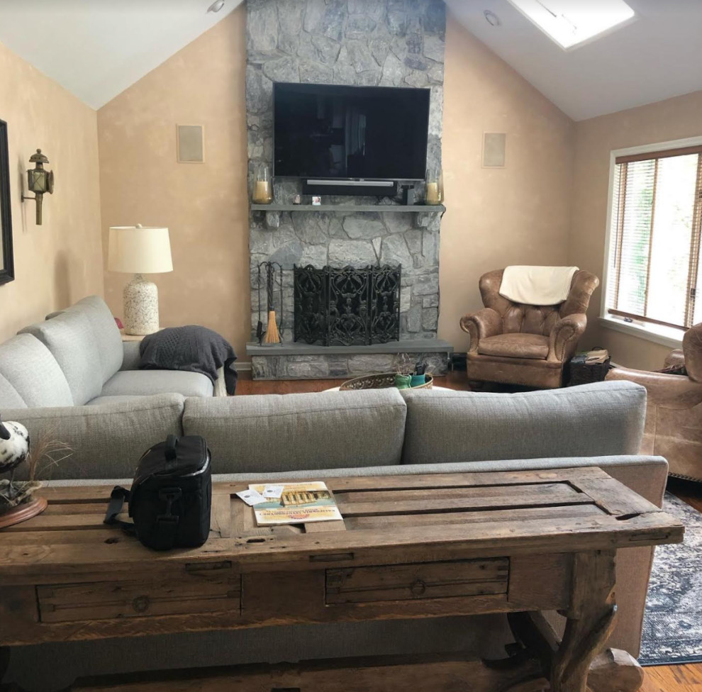 Diseño de sala de estar abierta y abovedada tradicional renovada con paredes beige, suelo de madera en tonos medios, todas las chimeneas, marco de chimenea de piedra, televisor colgado en la pared y suelo marrón