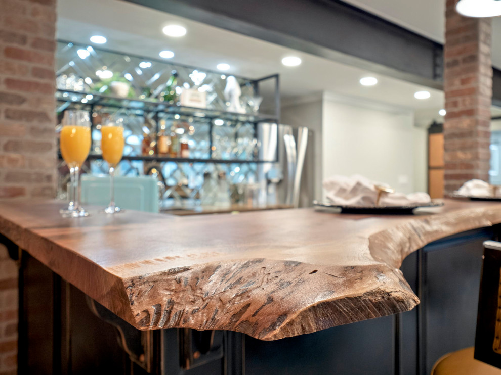 Large eclectic l-shaped concrete floor and gray floor seated home bar photo with an undermount sink, recessed-panel cabinets, black cabinets, wood countertops, mirror backsplash and brown countertops