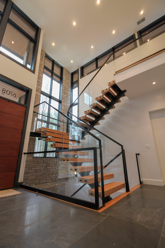 Идея дизайна: большая лестница на больцах в стиле модернизм с деревянными ступенями