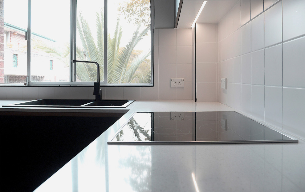 Photo of a small scandinavian u-shaped eat-in kitchen in Sydney with a double-bowl sink, black cabinets, white splashback, medium hardwood floors and white benchtop.