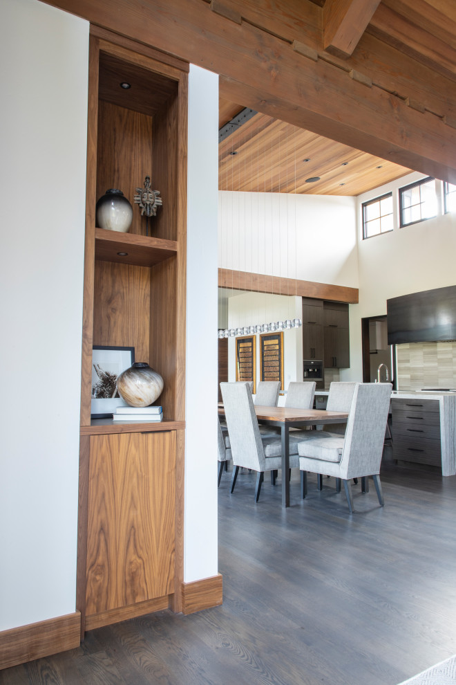 Medium tone wood floor and vaulted ceiling kitchen photo with an undermount sink, flat-panel cabinets, dark wood cabinets, quartz countertops, beige backsplash, porcelain backsplash, stainless steel appliances and an island