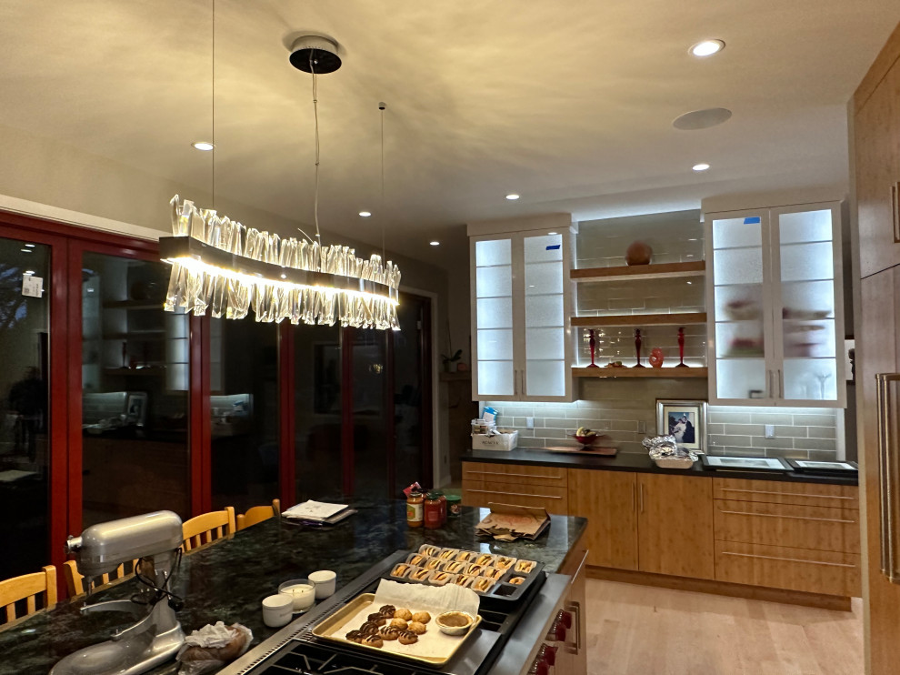 Design ideas for a medium sized contemporary single-wall kitchen/diner in San Francisco with glass-front cabinets, white cabinets, grey splashback, glass tiled splashback, integrated appliances, light hardwood flooring, an island, yellow floors and black worktops.