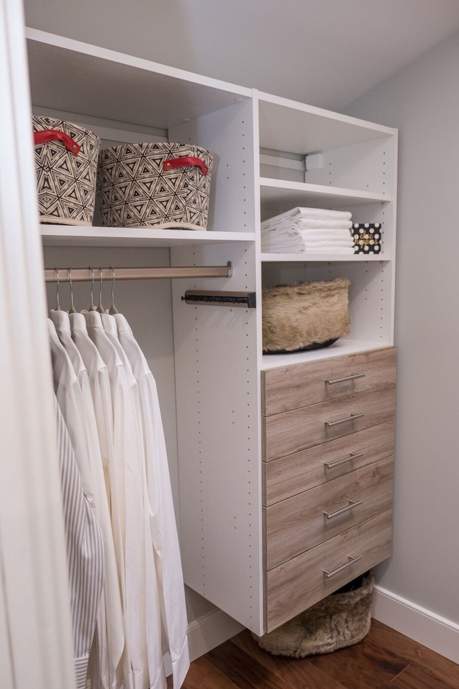 Design ideas for a small transitional gender-neutral walk-in wardrobe in Toronto with medium hardwood floors, brown floor and light wood cabinets.