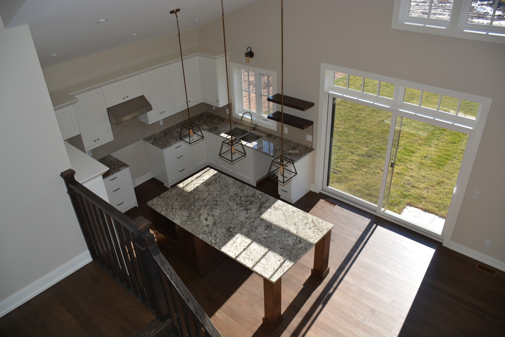 Mid-sized transitional u-shaped light wood floor eat-in kitchen photo in Toronto with a double-bowl sink, shaker cabinets, white cabinets, granite countertops, gray backsplash, subway tile backsplash, stainless steel appliances and an island