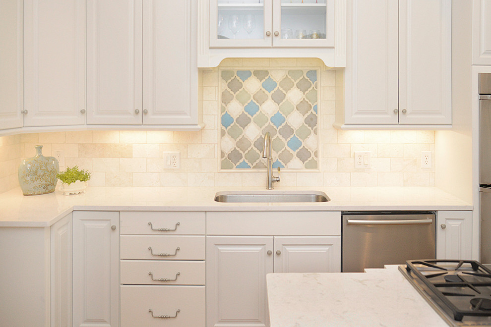 Transitional light wood floor kitchen photo with white cabinets, beige backsplash, stainless steel appliances and an island
