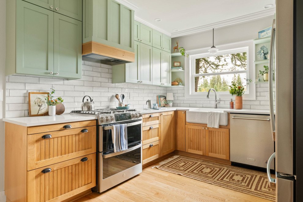 Kitchen - traditional u-shaped light wood floor and beige floor kitchen idea in Portland with a farmhouse sink, shaker cabinets, green cabinets, white backsplash, subway tile backsplash, stainless steel appliances and white countertops