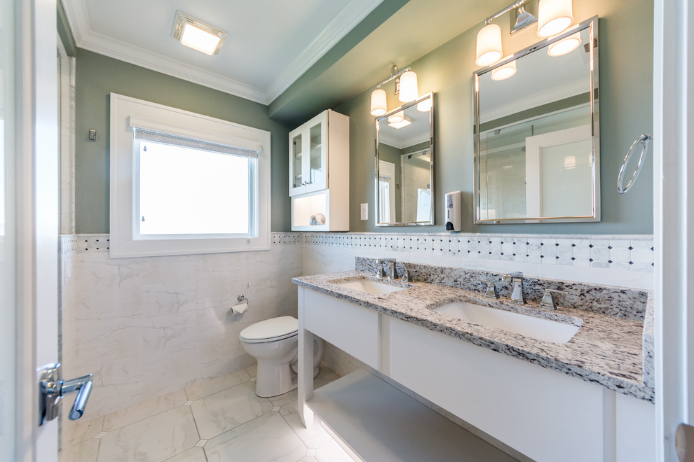Photo of a mid-sized transitional 3/4 bathroom in Other with flat-panel cabinets, white cabinets, a shower/bathtub combo, a two-piece toilet, white tile, ceramic tile, blue walls, marble floors, an undermount sink, granite benchtops, white floor and a hinged shower door.