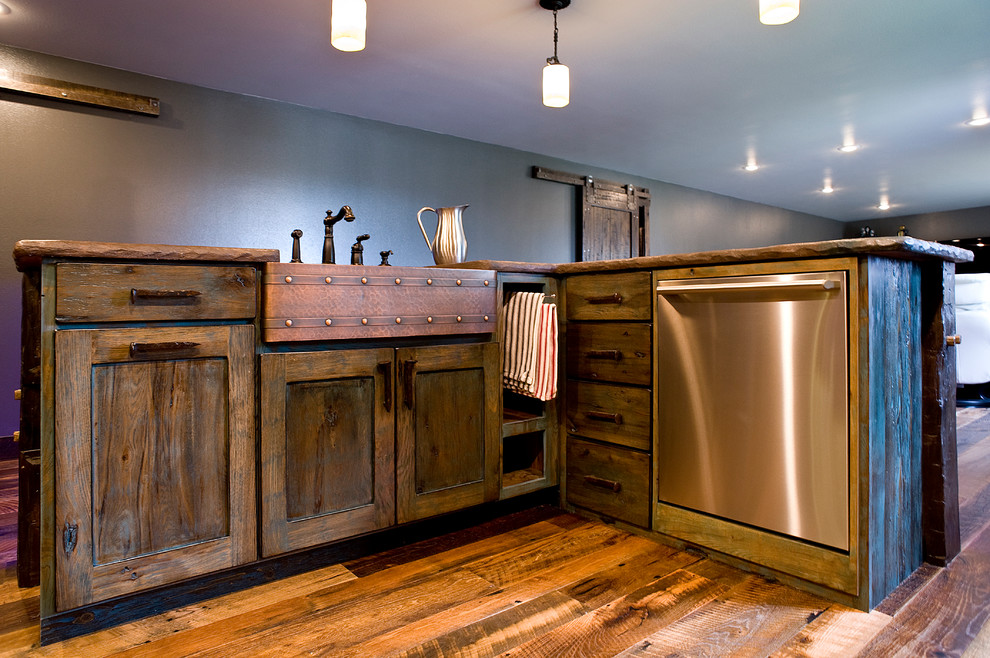 Mid-sized mountain style l-shaped dark wood floor and brown floor enclosed kitchen photo with a farmhouse sink, shaker cabinets, dark wood cabinets, wood countertops, stainless steel appliances and an island