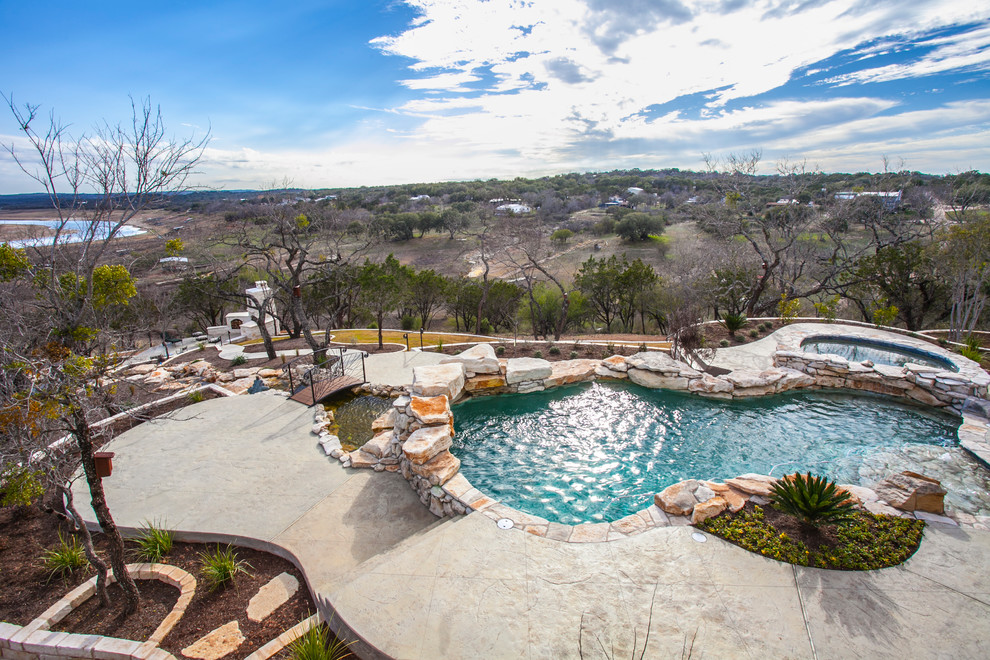 Hot tub - large rustic backyard stamped concrete and custom-shaped hot tub idea in Austin