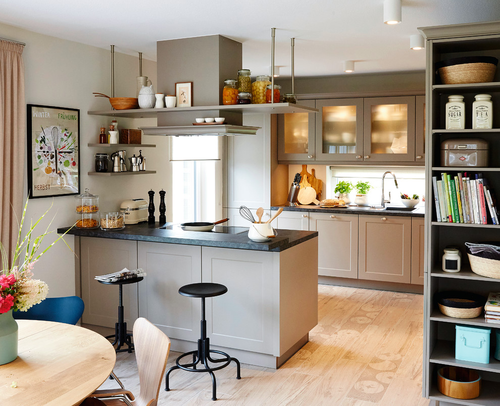 Offene, Mittelgroße, Zweizeilige Moderne Küchenbar mit schwarzer Arbeitsplatte, Schrankfronten im Shaker-Stil, grauen Schränken, Halbinsel, beigem Boden, Einbauwaschbecken, Rückwand-Fenster und hellem Holzboden in Hamburg