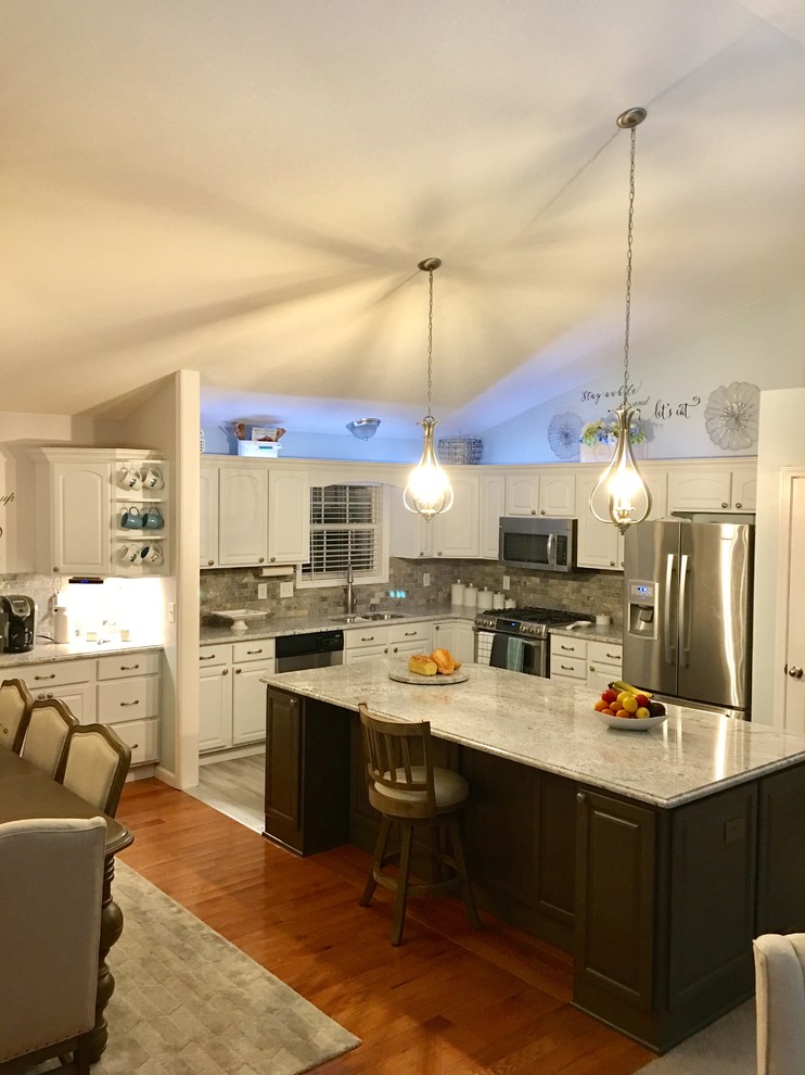 Eat-in kitchen - mid-sized l-shaped eat-in kitchen idea with an undermount sink, raised-panel cabinets, dark wood cabinets, granite countertops, multicolored backsplash, subway tile backsplash, stainless steel appliances and an island