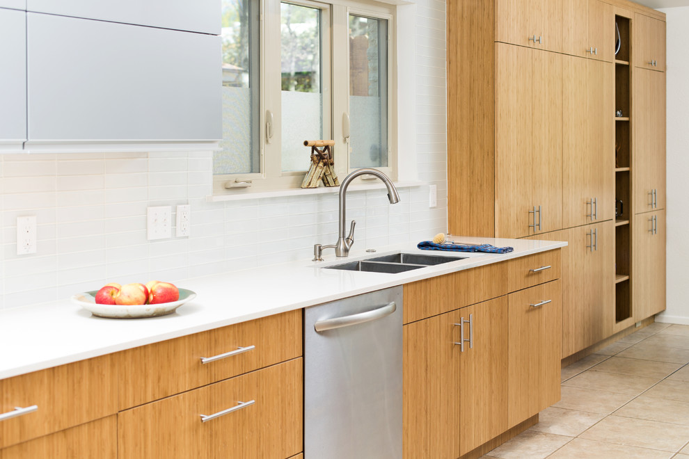 Large midcentury galley eat-in kitchen in Dallas with a double-bowl sink, flat-panel cabinets, medium wood cabinets, quartz benchtops, white splashback, glass tile splashback, stainless steel appliances, travertine floors and no island.