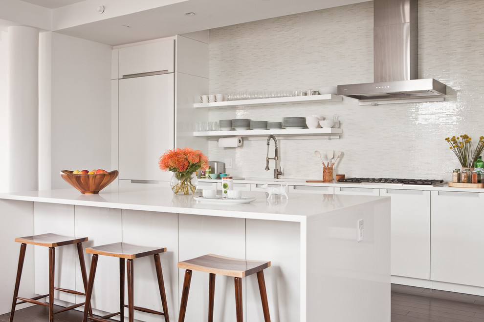 This is an example of a contemporary galley kitchen in New York with an undermount sink, flat-panel cabinets, white cabinets, white splashback, panelled appliances, dark hardwood floors and a peninsula.
