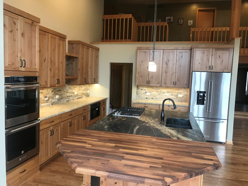 Example of a large mountain style l-shaped medium tone wood floor and brown floor open concept kitchen design in Chicago with an undermount sink, shaker cabinets, medium tone wood cabinets, granite countertops, green backsplash, slate backsplash, stainless steel appliances, an island and black countertops