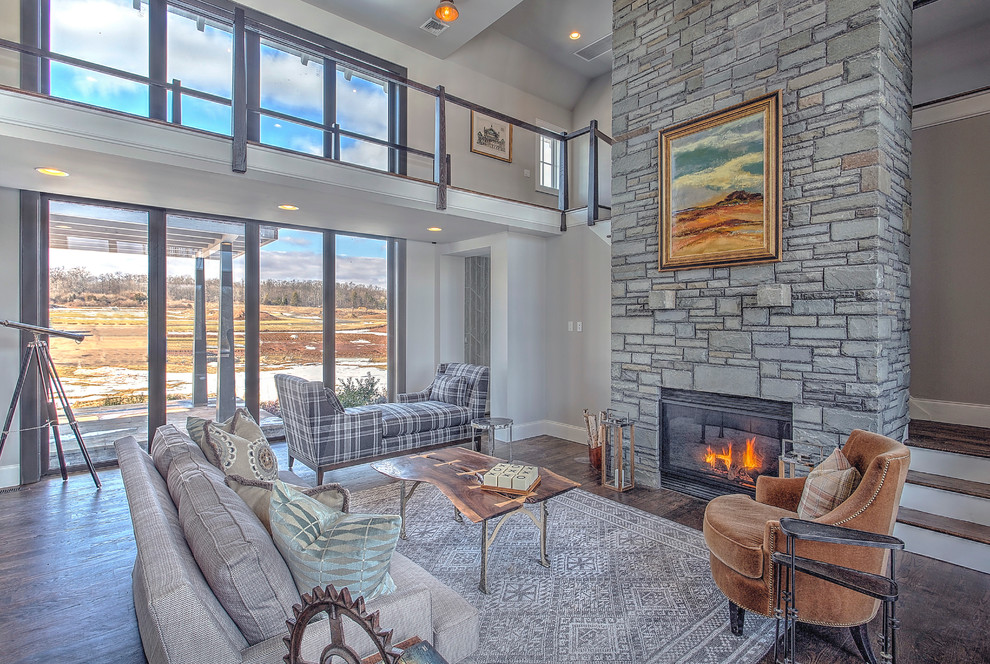 Large country open concept family room in New York with grey walls, dark hardwood floors, a standard fireplace, a stone fireplace surround and a wall-mounted tv.