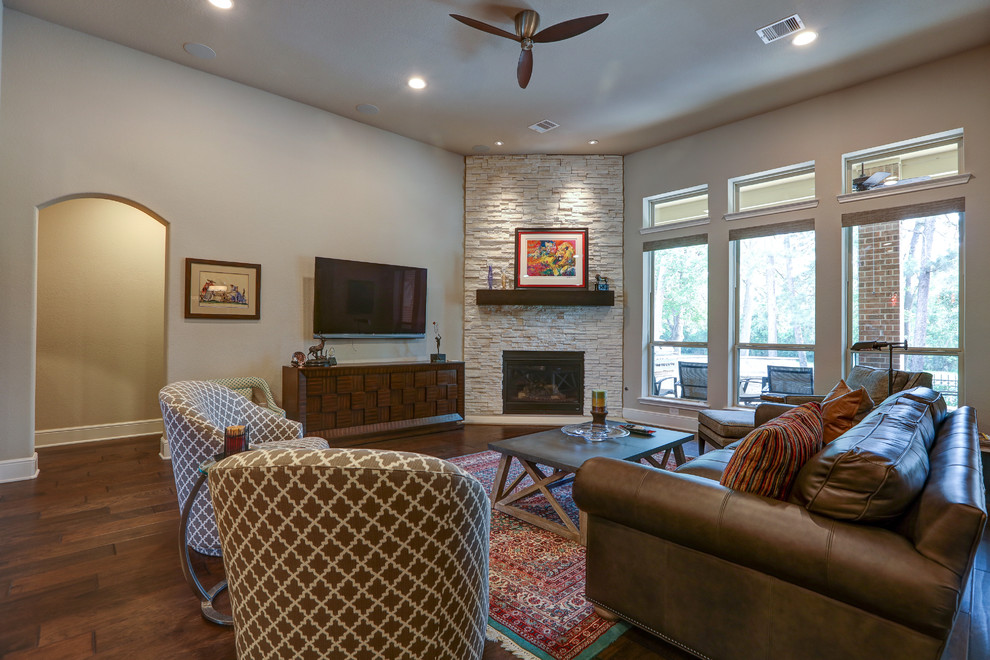 Large contemporary open concept living room in Houston with grey walls, dark hardwood floors, a corner fireplace, a stone fireplace surround, a wall-mounted tv and brown floor.