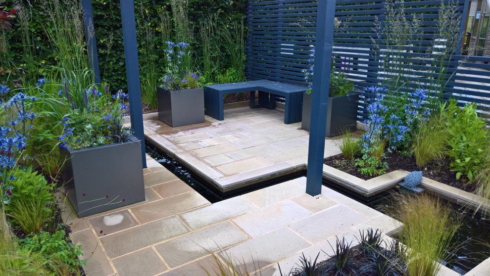 This is an example of a small contemporary courtyard garden in Other with with pond and a wood fence.