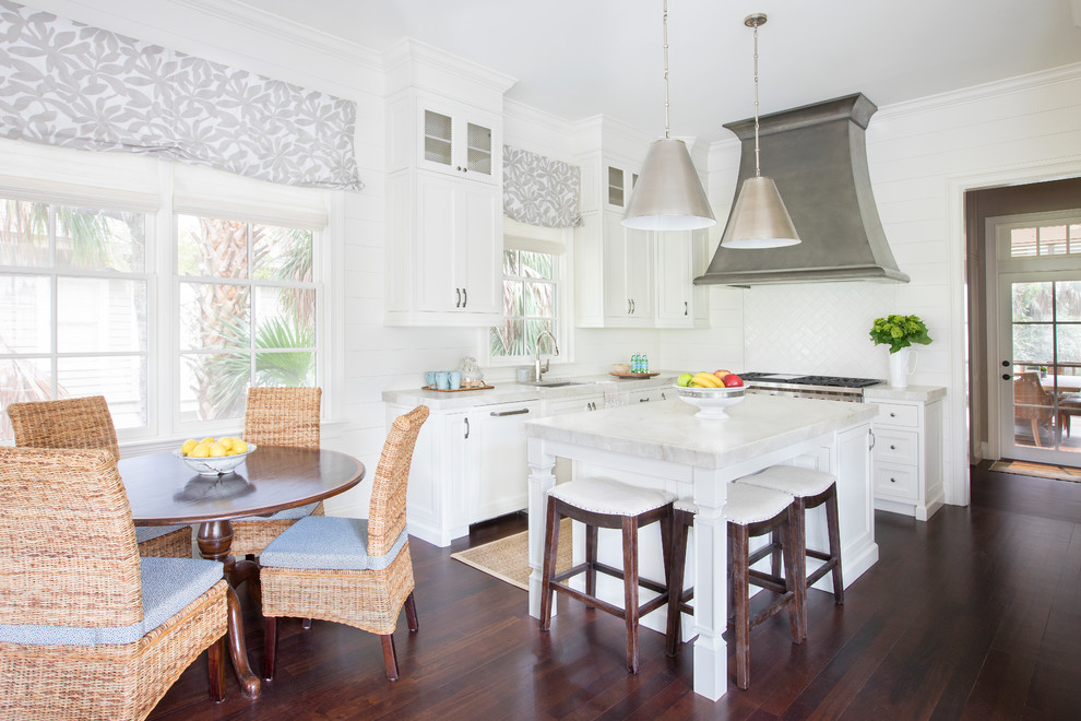 Beach style l-shaped kitchen in Charleston with an undermount sink, shaker cabinets, white cabinets, white splashback, dark hardwood floors, with island, brown floor and white benchtop.