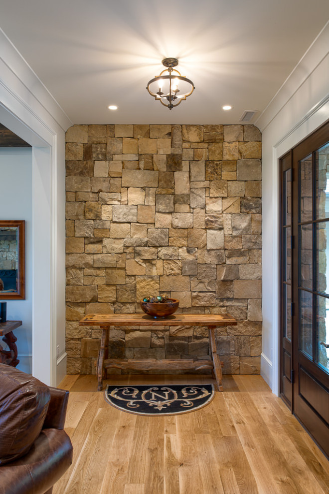 Transitional medium tone wood floor and brown floor foyer photo with a dark wood front door