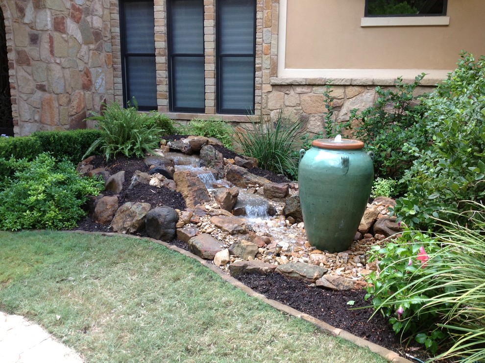 This is an example of a mid-sized front yard partial sun garden in Austin with a water feature and mulch.