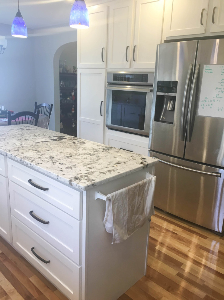 Eat-in kitchen - mid-sized transitional u-shaped medium tone wood floor and brown floor eat-in kitchen idea with recessed-panel cabinets, white cabinets, granite countertops, stainless steel appliances, an island and multicolored countertops