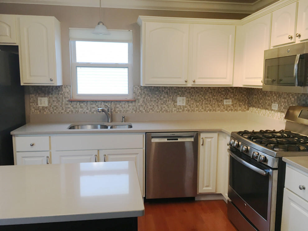 This is an example of a mid-sized traditional l-shaped eat-in kitchen in Chicago with raised-panel cabinets, white cabinets, quartz benchtops and with island.