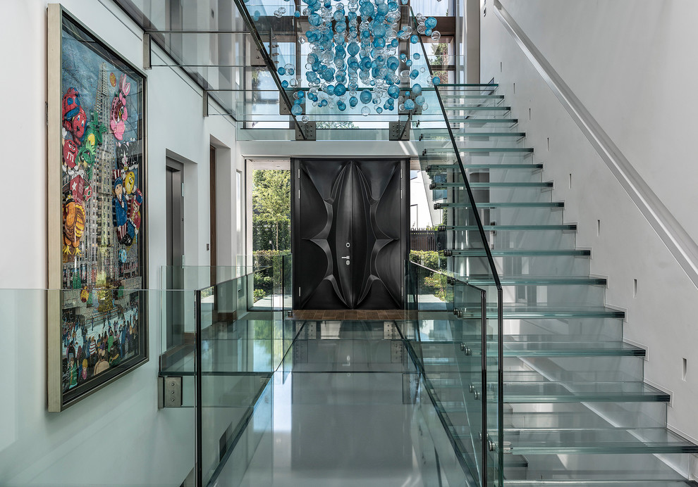 This is an example of a large contemporary glass floating staircase in Hampshire with glass risers.