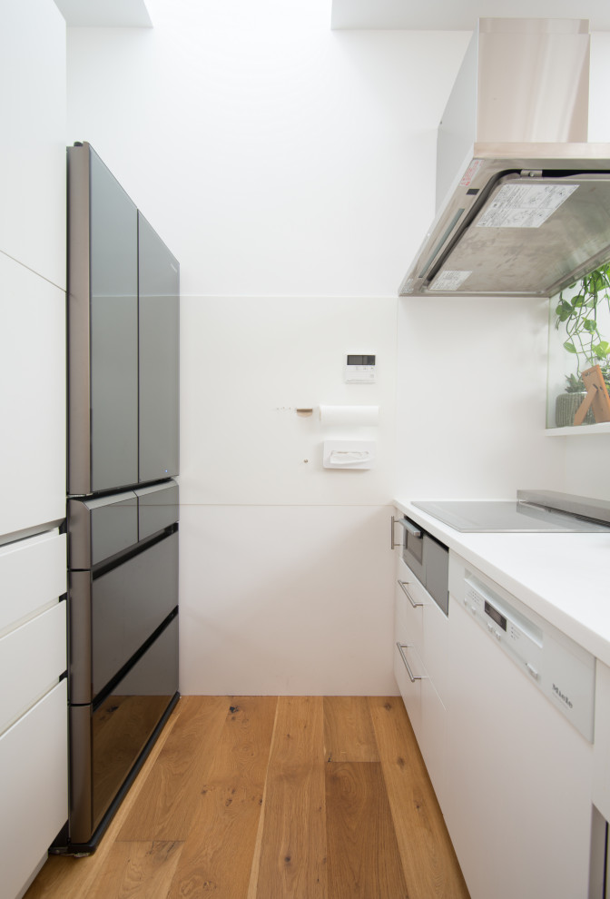 Design ideas for a modern single-wall open plan kitchen in Tokyo with a submerged sink, beaded cabinets, white cabinets, composite countertops, white splashback, white appliances, medium hardwood flooring, a breakfast bar, beige floors, white worktops and a drop ceiling.