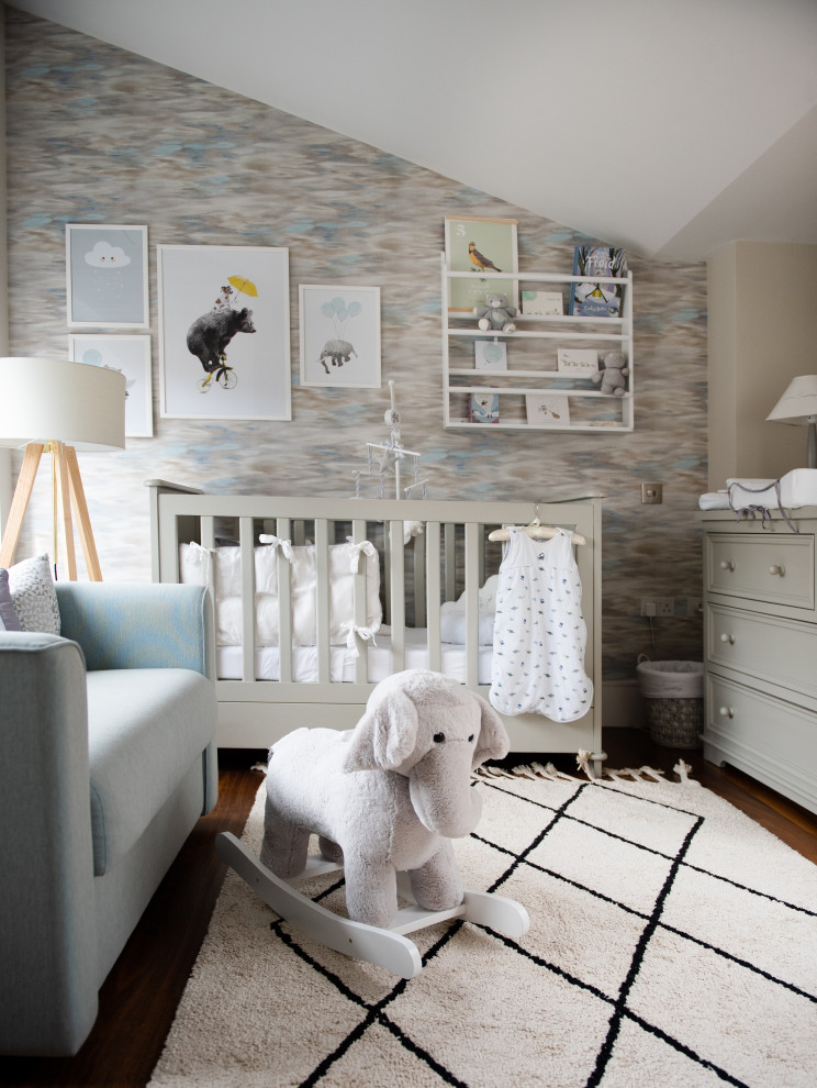 Small contemporary nursery in London with beige walls, medium hardwood floors, brown floor and wallpaper for girls.