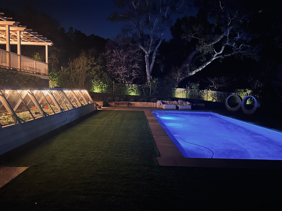 Diseño de piscina natural tradicional grande rectangular en patio trasero con paisajismo de piscina y adoquines de piedra natural