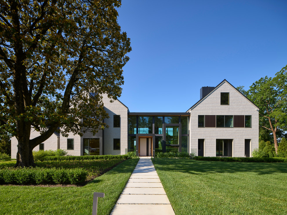 Стильный дизайн: большой, двухэтажный, разноцветный частный загородный дом в стиле модернизм с комбинированной облицовкой, двускатной крышей, металлической крышей, черной крышей, отделкой дранкой и входной группой - последний тренд
