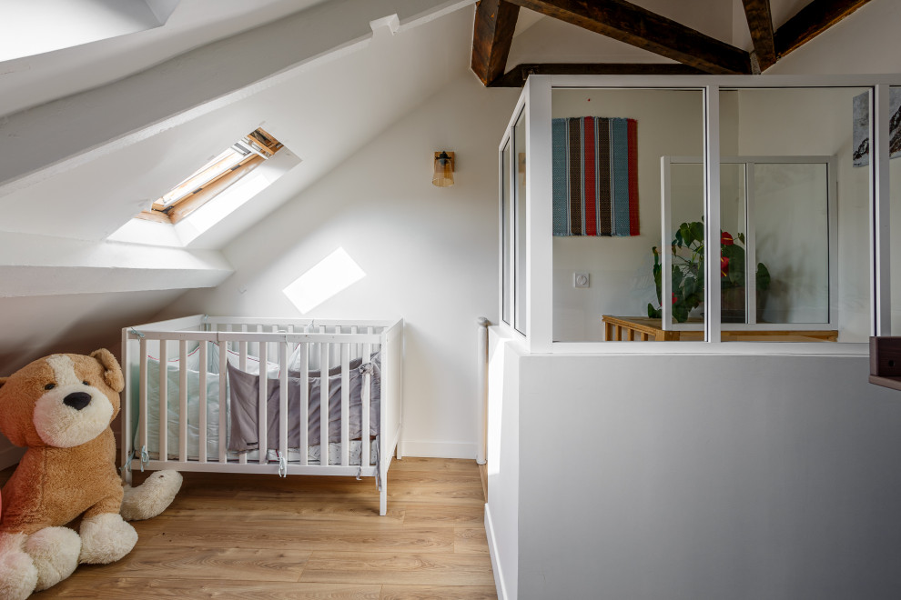Réalisation d'une petite chambre de bébé champêtre avec parquet clair, un sol beige et poutres apparentes.