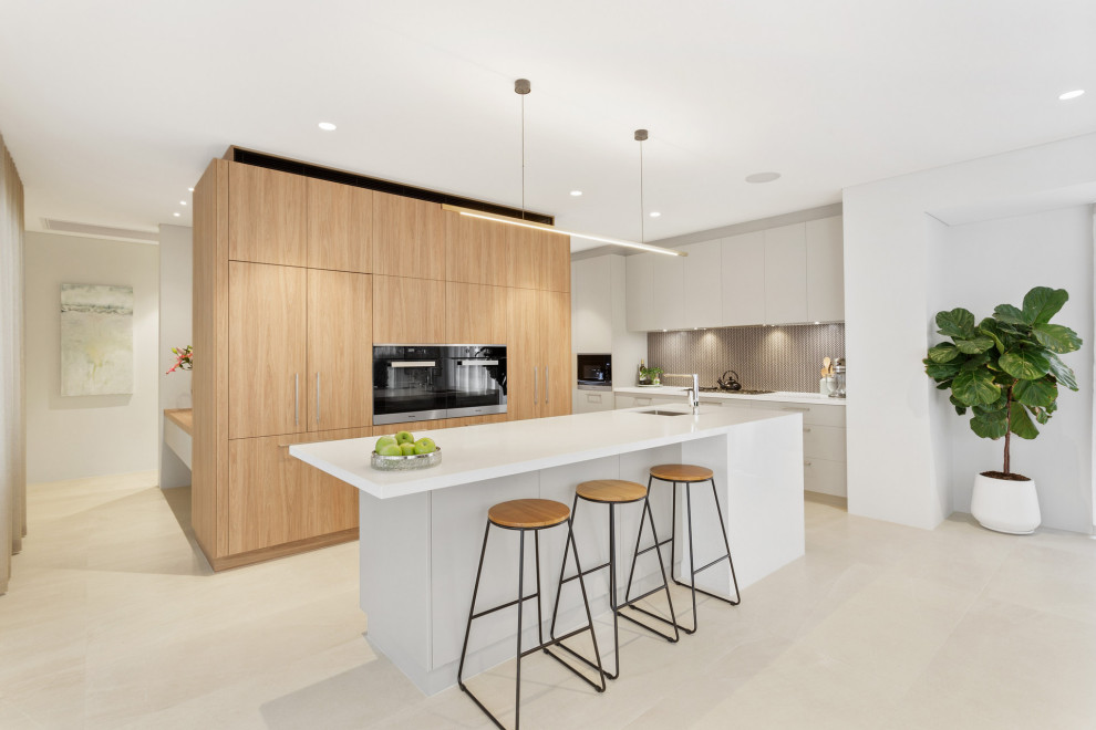 Contemporary l-shaped kitchen in Perth with an undermount sink, flat-panel cabinets, white cabinets, grey splashback, mosaic tile splashback, black appliances, with island, grey floor and white benchtop.