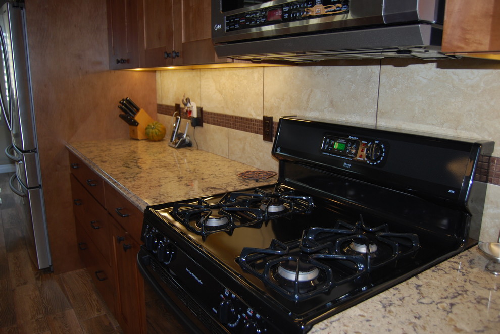 Mid-sized mountain style l-shaped porcelain tile and brown floor eat-in kitchen photo with an undermount sink, medium tone wood cabinets, beige backsplash, porcelain backsplash, shaker cabinets, quartz countertops, stainless steel appliances and an island