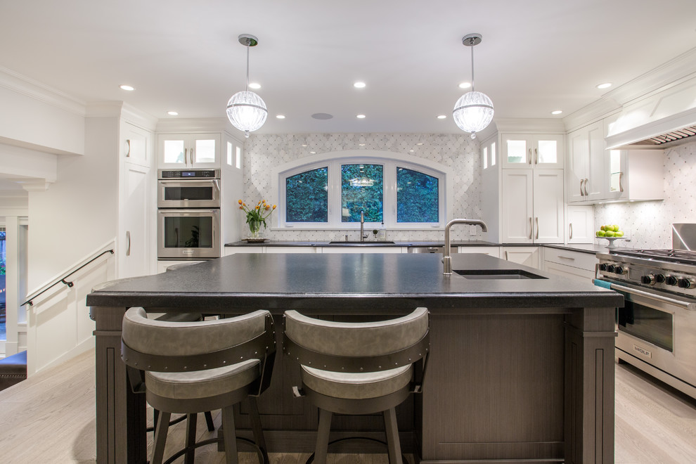 Inspiration for a large transitional l-shaped medium tone wood floor and beige floor eat-in kitchen remodel in Vancouver with an undermount sink, shaker cabinets, white cabinets, granite countertops, gray backsplash, marble backsplash, stainless steel appliances, an island and black countertops