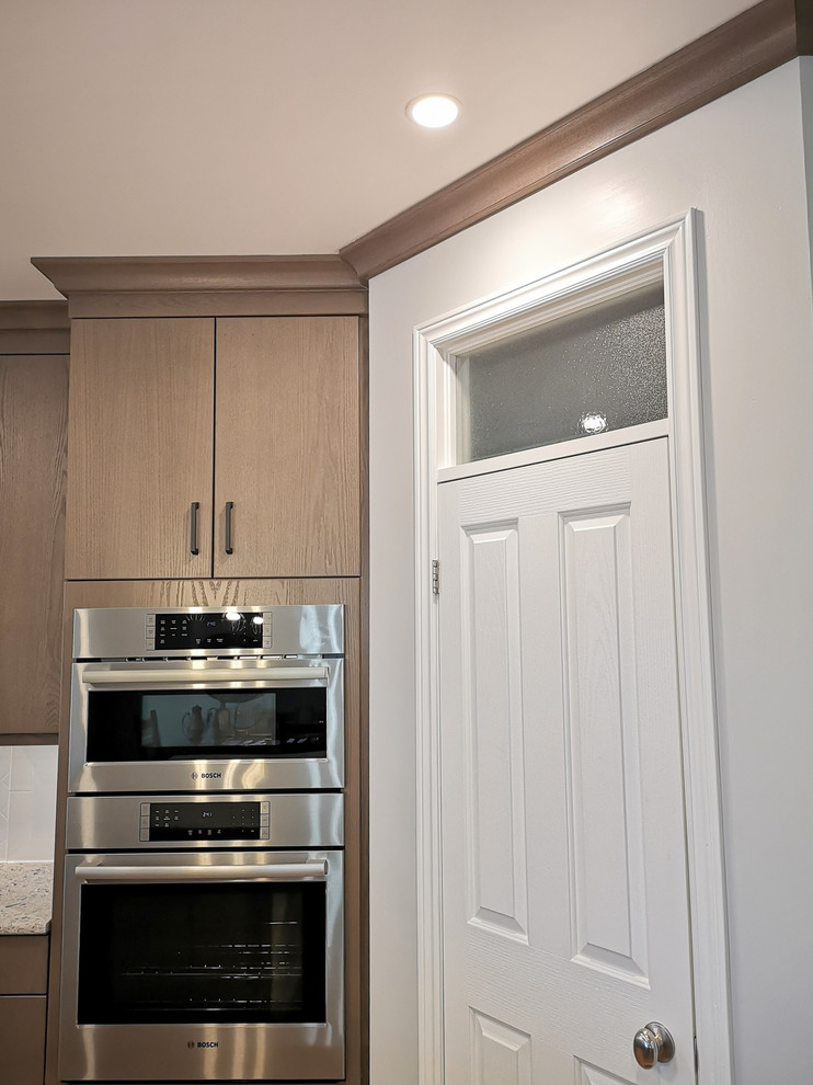Eat-in kitchen - large transitional u-shaped light wood floor and brown floor eat-in kitchen idea with an undermount sink, flat-panel cabinets, beige cabinets, quartz countertops, white backsplash, subway tile backsplash, stainless steel appliances, an island and white countertops