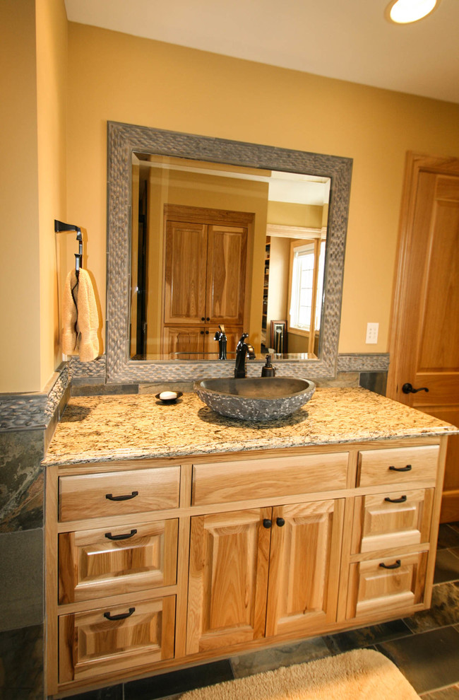 Inspiration for a mid-sized rustic multicolored tile and stone tile slate floor drop-in bathtub remodel in Minneapolis with a vessel sink, raised-panel cabinets, light wood cabinets, granite countertops, a two-piece toilet and yellow walls