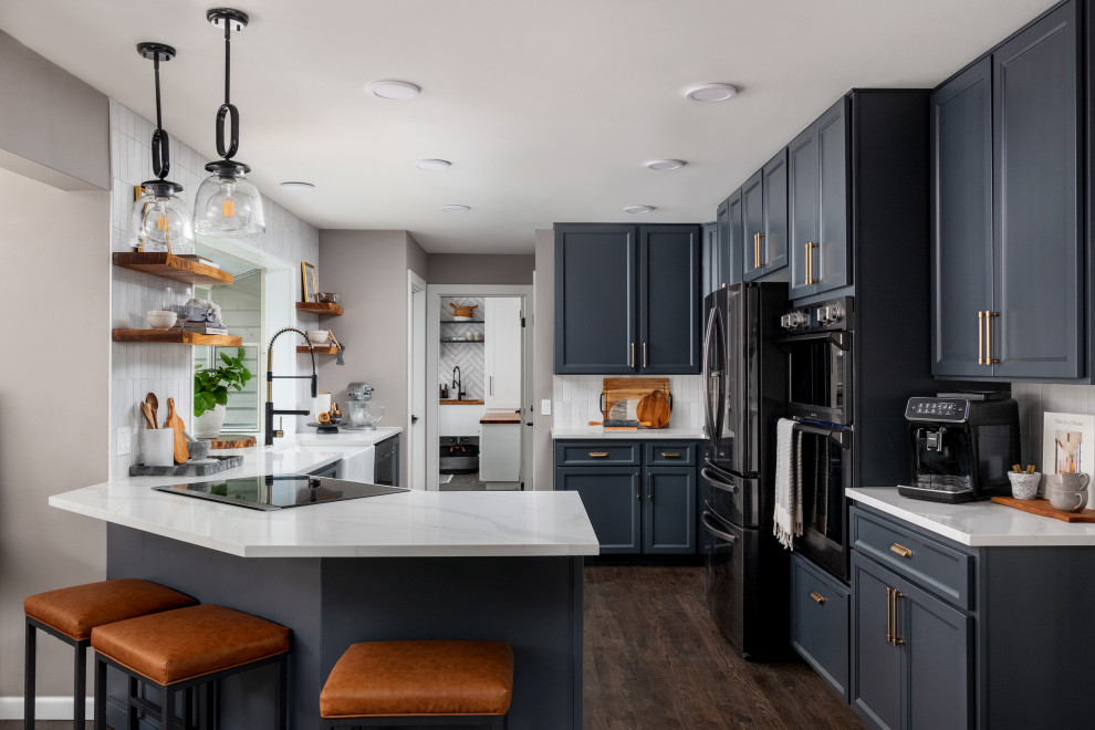 Example of a mid-sized transitional l-shaped dark wood floor and brown floor eat-in kitchen design in Seattle with a farmhouse sink, shaker cabinets, blue cabinets, quartz countertops, white backsplash, ceramic backsplash, stainless steel appliances, a peninsula and white countertops