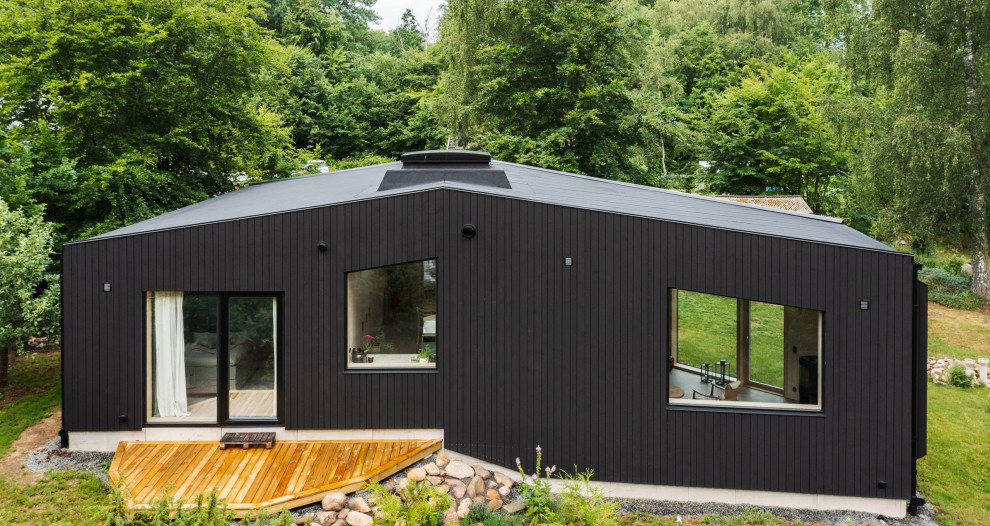Idée de décoration pour une façade de maison noire minimaliste en bois et bardage à clin de taille moyenne et de plain-pied avec un toit à deux pans et un toit noir.