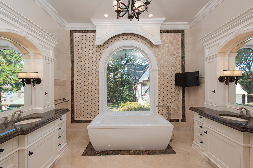 Photo of an expansive traditional master bathroom in New York with furniture-like cabinets, white cabinets, a hot tub, beige tile, marble, beige walls, ceramic floors, an undermount sink, granite benchtops, beige floor and brown benchtops.