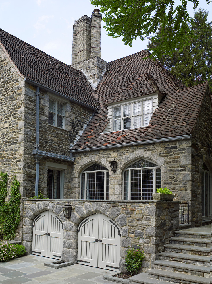 Large traditional three-storey brown house exterior in New York with stone veneer, a gable roof and a shingle roof.