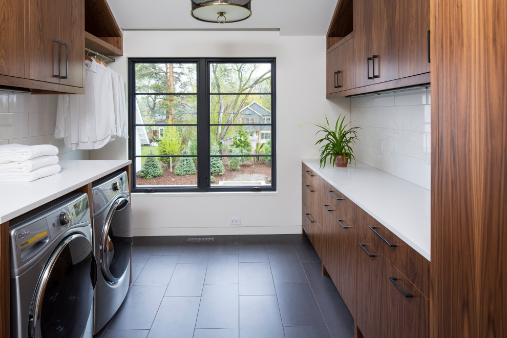 Large trendy galley ceramic tile and black floor dedicated laundry room photo in Minneapolis with flat-panel cabinets, dark wood cabinets, solid surface countertops, white walls, a side-by-side washer/dryer and white countertops