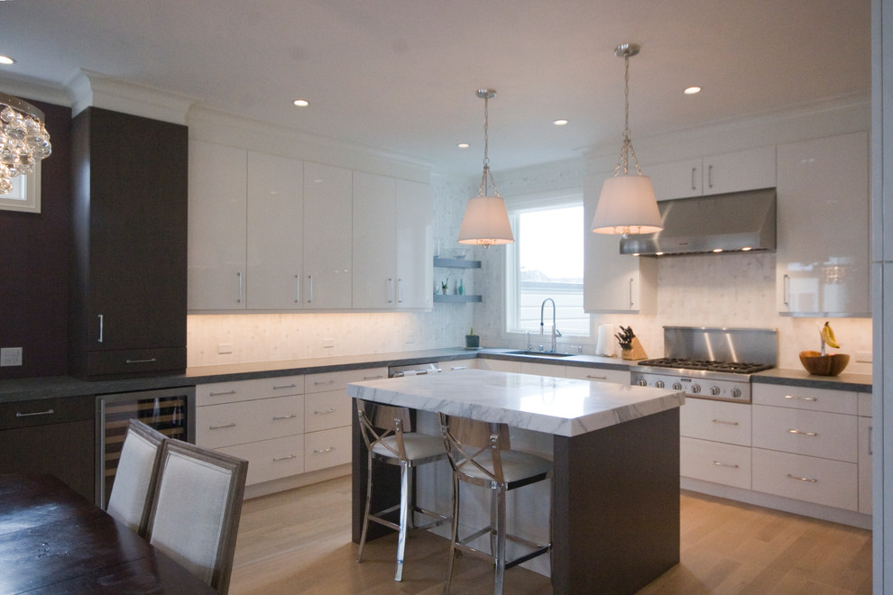 This is an example of a transitional u-shaped eat-in kitchen in San Francisco with a single-bowl sink, flat-panel cabinets, white cabinets, marble benchtops, stone tile splashback, stainless steel appliances, with island and light hardwood floors.