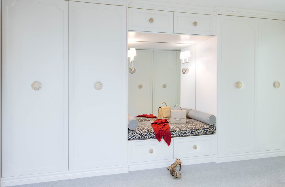 This is an example of a large transitional gender-neutral walk-in wardrobe in Toronto with white cabinets, carpet, white floor and recessed-panel cabinets.