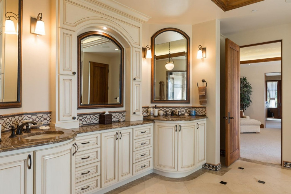Inspiration for a mediterranean master bathroom in San Francisco with raised-panel cabinets, marble benchtops, brown benchtops, beige cabinets, multi-coloured tile, beige walls, an undermount sink, multi-coloured floor and a double vanity.