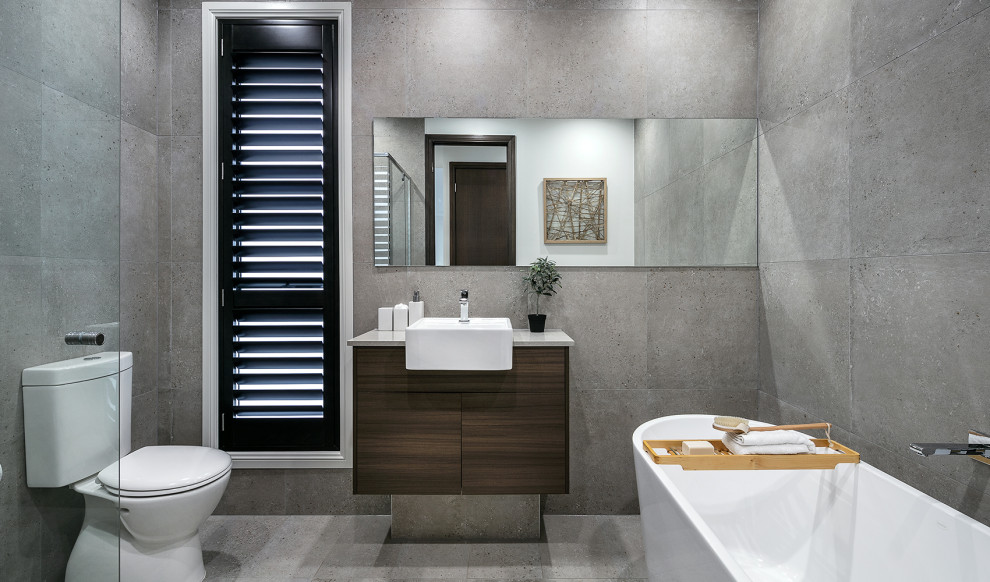 This is an example of a mid-sized contemporary 3/4 bathroom in Other with flat-panel cabinets, medium wood cabinets, a freestanding tub, a two-piece toilet, gray tile, a vessel sink, grey floor, grey benchtops, a single vanity and a floating vanity.