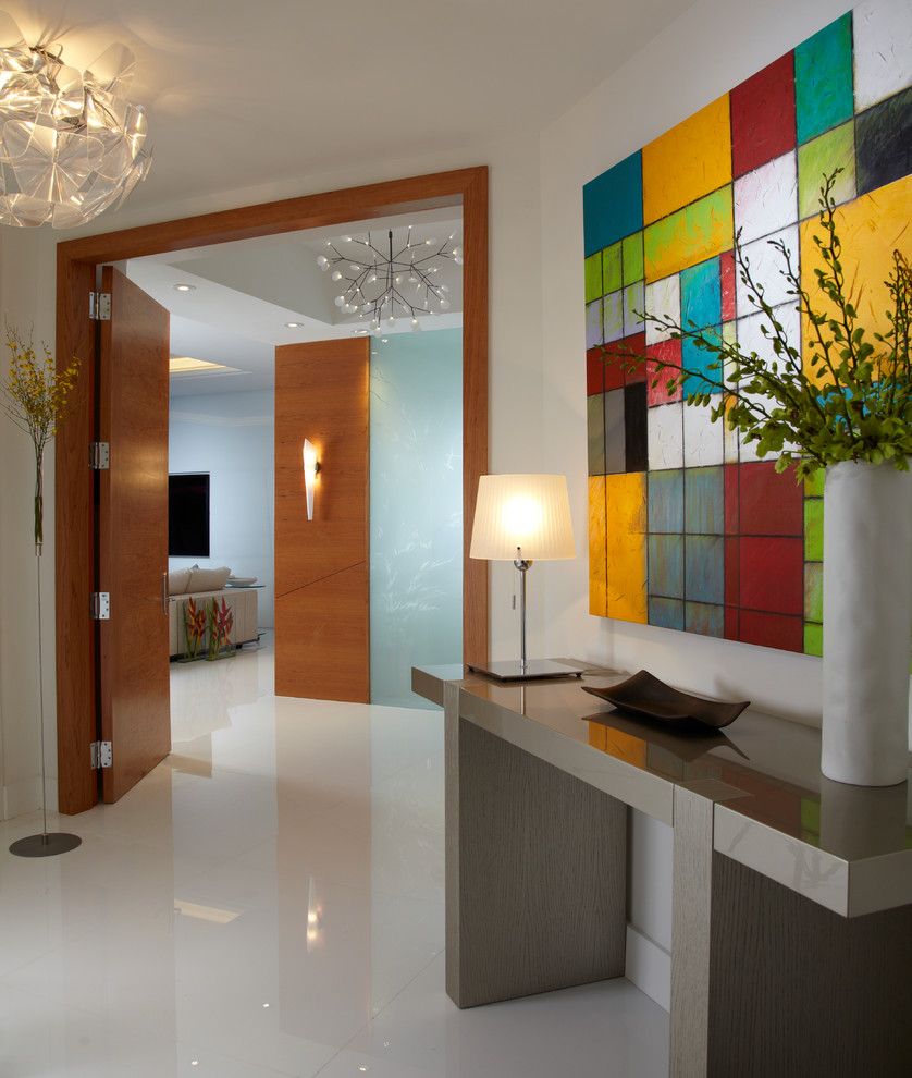 This is an example of a mid-sized contemporary vestibule in Miami with white walls, white floor, marble floors and a medium wood front door.