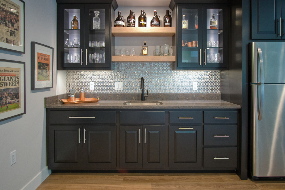This is an example of a transitional wet bar with an undermount sink, raised-panel cabinets, dark wood cabinets, quartz benchtops, metal splashback, vinyl floors, brown floor and brown benchtop.